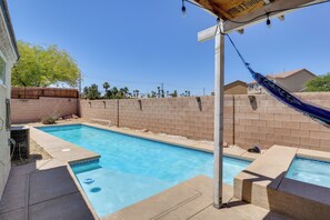 Une piscine avec une terrasse en bois et un mur de briques en arrière-plan.