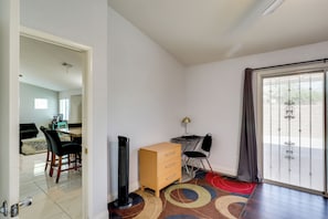 A room with a dining area, a desk, a chair, a radiator, a cabinet, and a large sliding glass door.