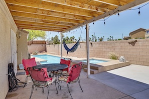 A covered patio with a pool, outdoor furniture, and a hammock.