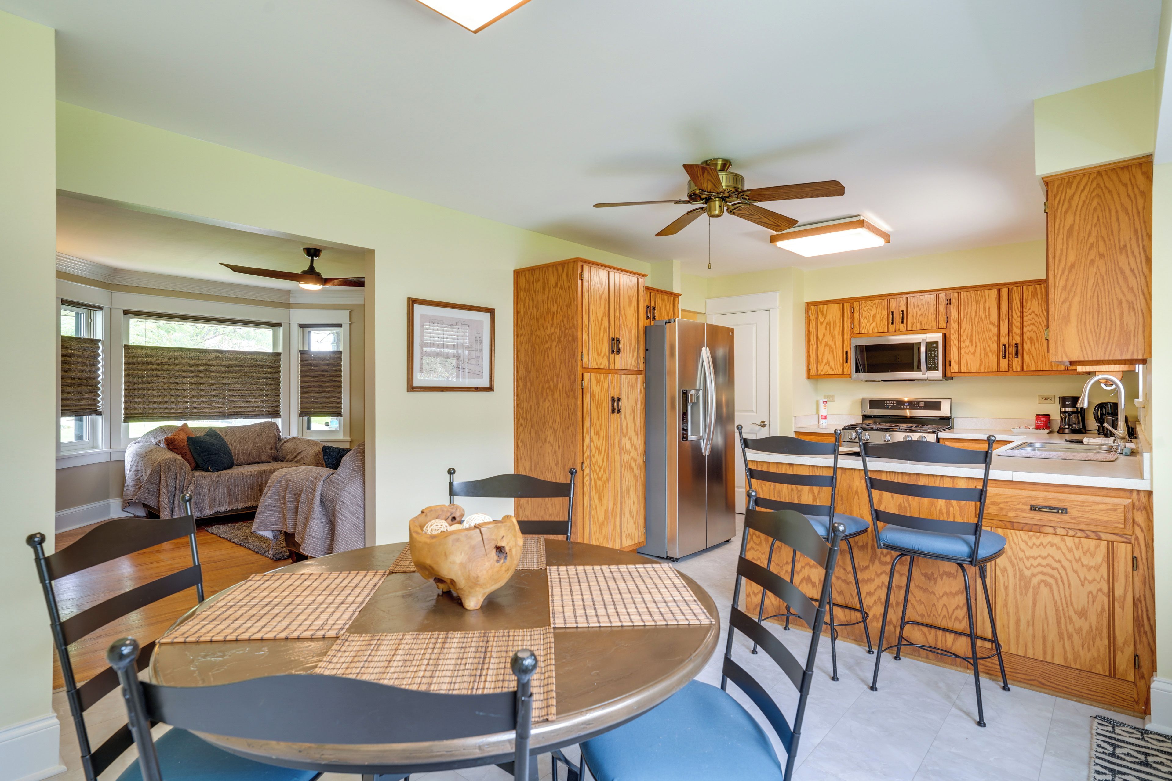A modern kitchen with wooden cabinets, a stainless steel refrigerator, and a microwave.