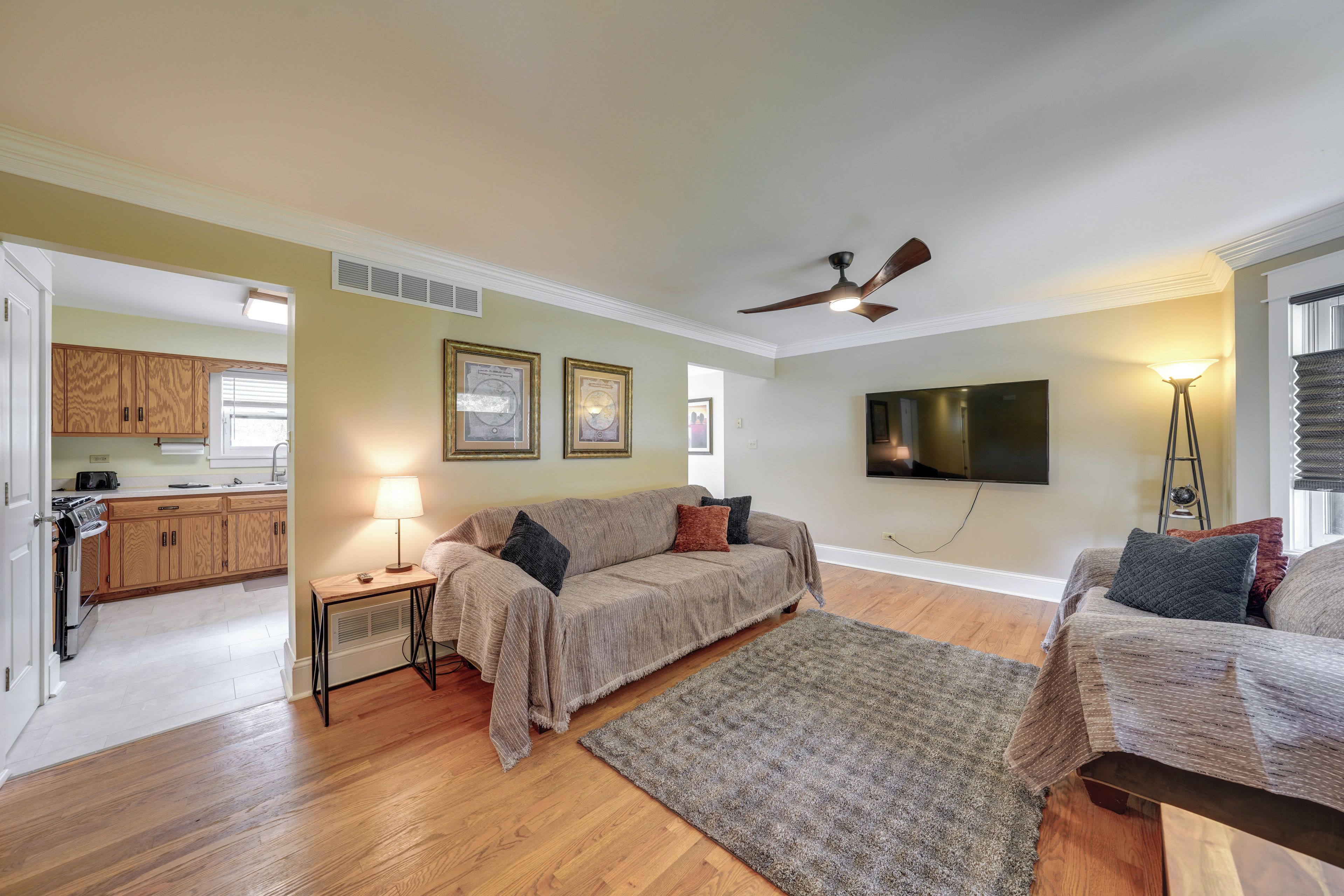 A living room with a sofa, a coffee table, a TV, and a ceiling fan.
