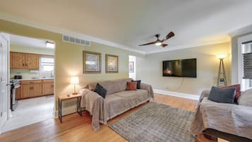 A living room with a sofa, a coffee table, a TV, and a ceiling fan.