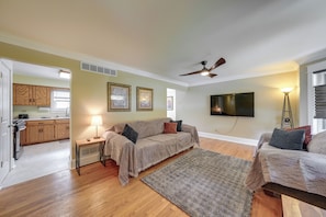 A living room with a sofa, a coffee table, a TV, and a ceiling fan.