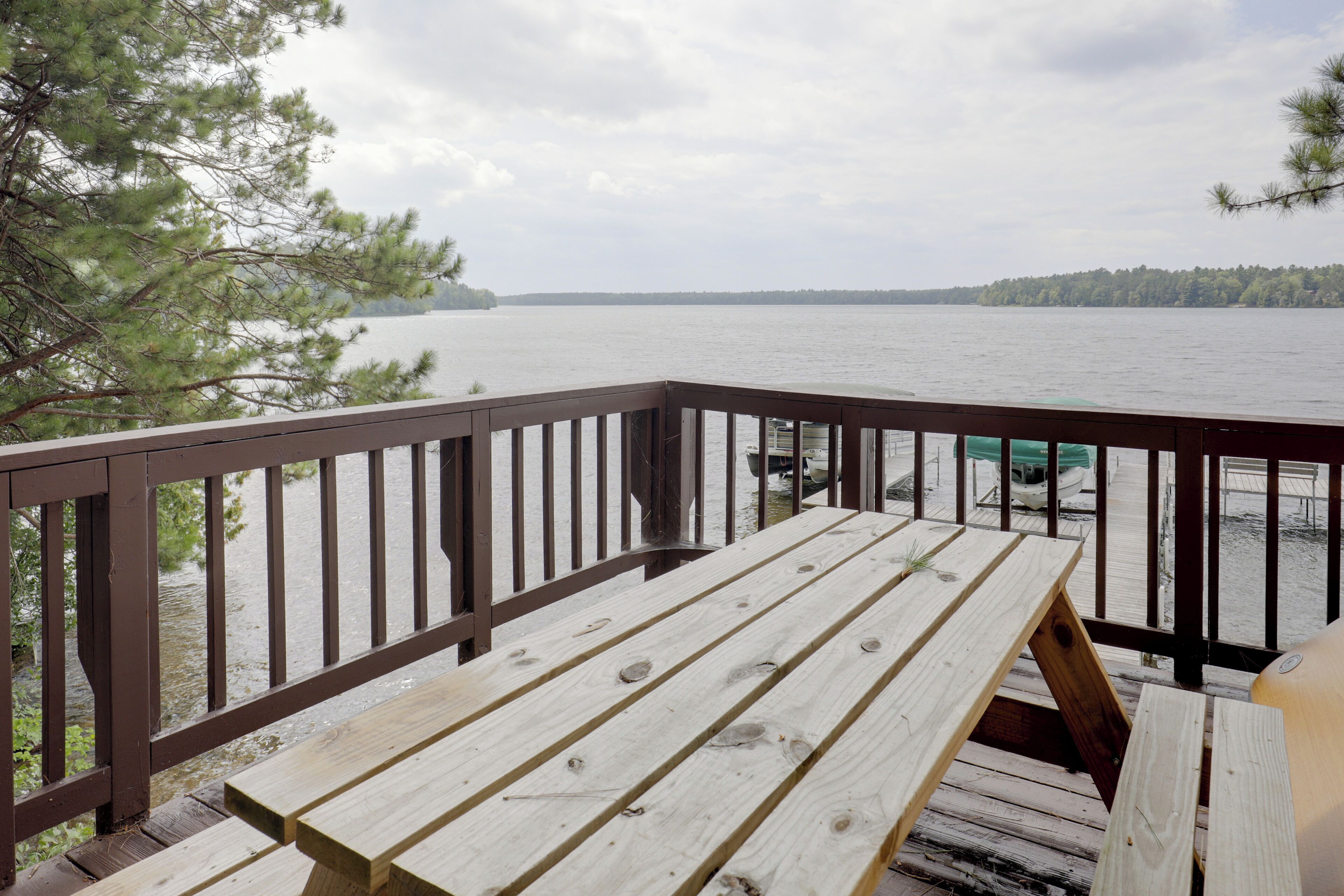 A wooden deck with a view of a lake and distant shoreline.