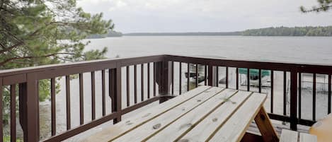 A wooden deck with a view of a lake and distant shoreline.