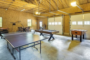 A recreational area with a ping pong table, foosball table, and a pool table.