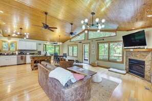 A spacious living area with a fireplace, a television, and a large window overlooking the outdoors. - Riverfront Home w/ Dock & Game Room in Lancaster! (Lancaster)