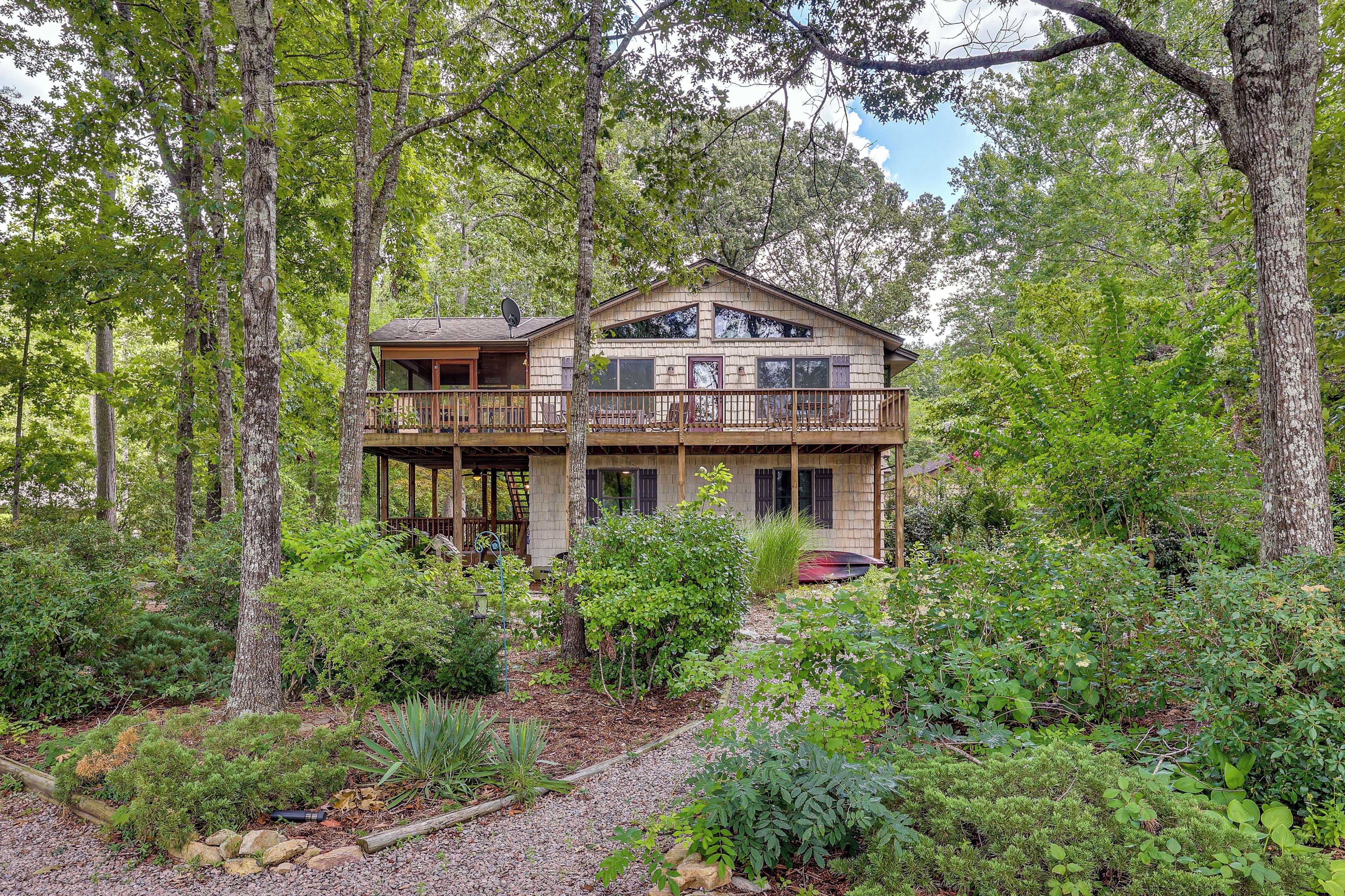 A two-story wooden cabin surrounded by dense forest.
