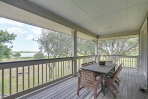 A covered outdoor area with a table and chairs, a view of trees and a body of water. - Bayou Views & Boat Dock on 12 Private Acres (Dickinson)