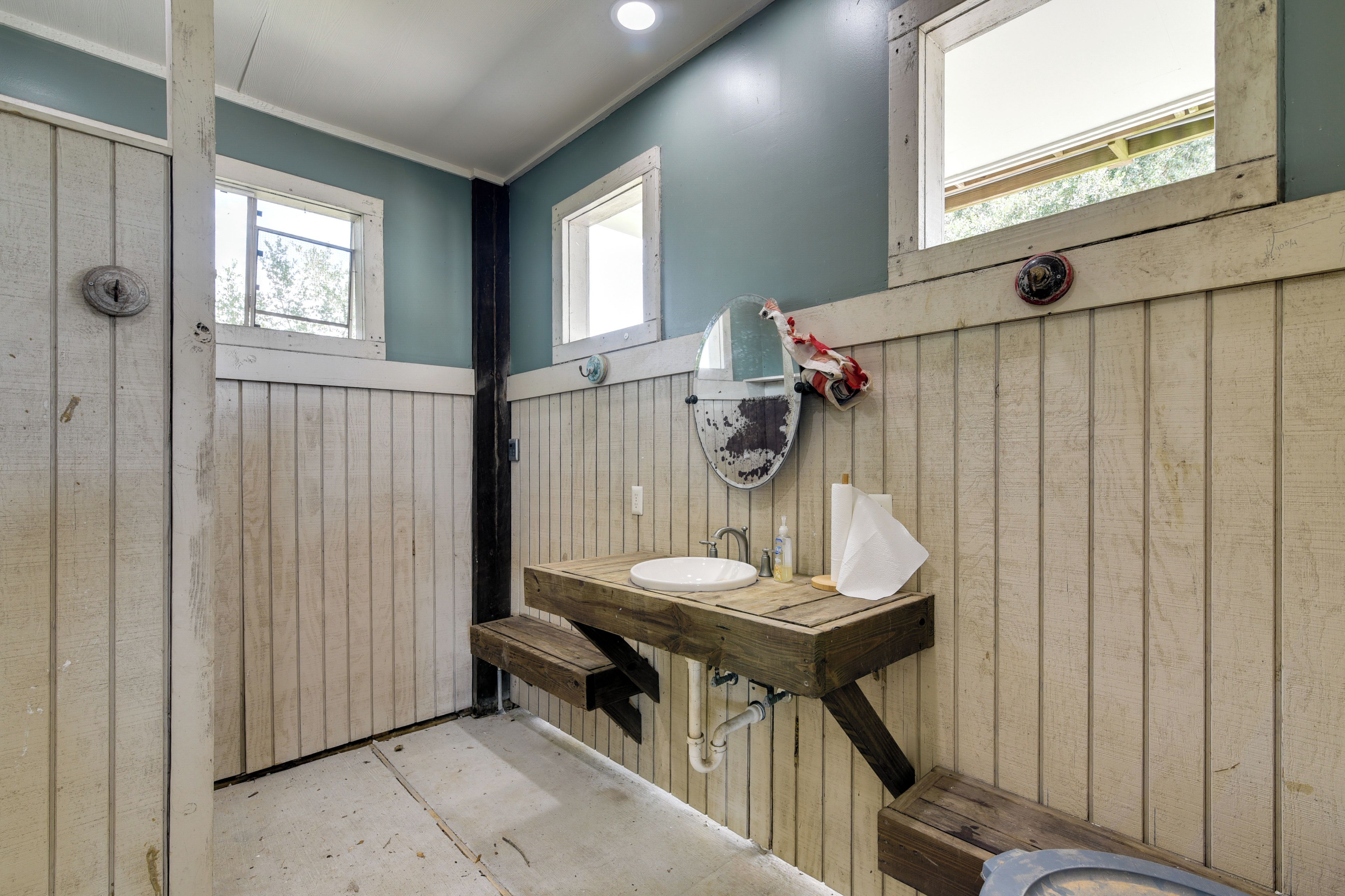 A rustic bathroom with wooden walls, a wooden sink, and a mirror.