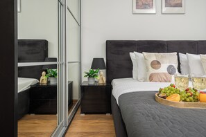 A modern bedroom with a large bed, bedside tables, a mirror, and a tray of fruit and glasses. - Lumina Comfort 3-Room Apt with Balcony (Warszawa)