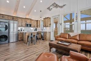 Eine moderne Küche mit Holzausstattung, einem Edelstahlkühlschrank und einer Kochinsel mit Barhocker.