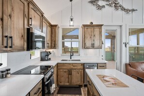 Eine moderne Küche mit Holzschränken, einer zentralen Kochinsel und Blick ins Freie.