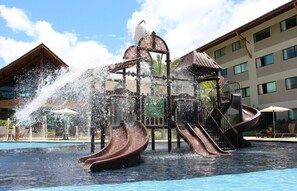 A water play area with slides and a fountain, surrounded by a pool and hotel buildings. - Muro Alto - Samoa Polynesia - Porto de Galinhas - Ground floor apartment with private pool. (N. Sra. do Ó)