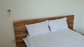 A bedroom with a wooden headboard, a white bedspread, and three abstract paintings on the wall.
