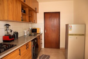 Una cucina compatta con mobili in legno, un forno a microonde, un frigorifero, una lavatrice e un fornello a gas.