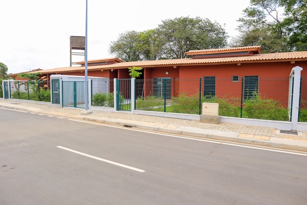 A building with a red facade, a tiled roof, and a fenced perimeter.
