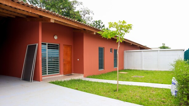 A residential building with a red exterior, a wooden door, and a small tree in the front yard. - Beautiful villa in Porto-Novo Benin (Porto-novo)