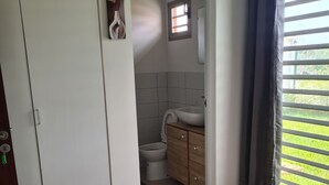 A bedroom with a bed, a wardrobe, a bathroom with a sink and toilet, and a window with curtains. - Beautiful villa in Porto-Novo Benin (Porto-novo)