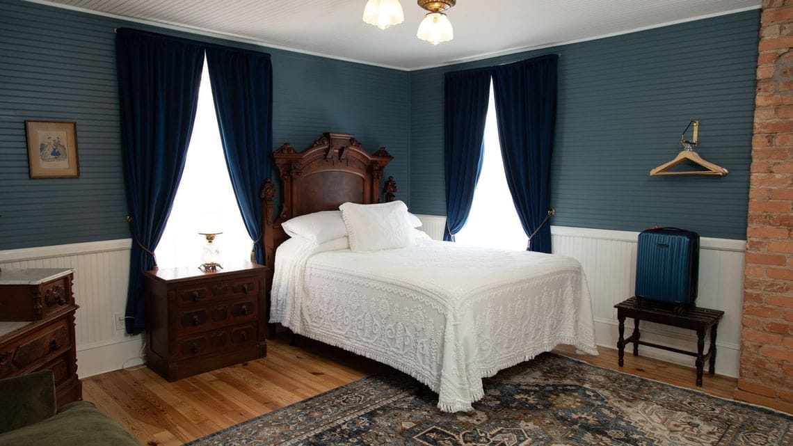 Une chambre à coucher avec un grand lit, une commode en bois et un porte-manteau mural.