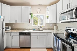 A modern kitchen with white cabinets, stainless steel appliances, a microwave, and a dishwasher.