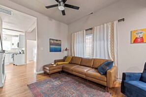 A living room with a brown leather sofa, a patterned rug, a blue armchair, and a painting on the wall.