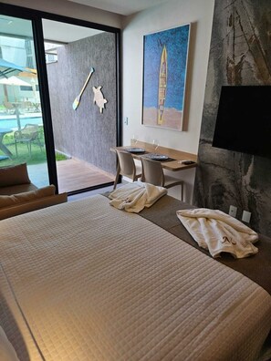 A hotel room with a large bed, a desk, and a view of the outdoor area. - F4.009 | Practicality, charm and comfort/Carneiros (Tamandaré)