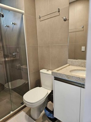 Een badkamer met een douchecabine, een toilet en een wastafel met een granieten aanrechtblad.