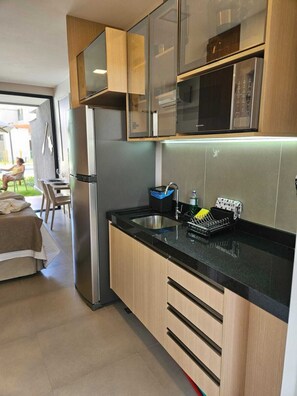A compact kitchen with a refrigerator, sink, and wooden cabinets. - F4.009 | Practicality, charm and comfort/Carneiros (Tamandaré)