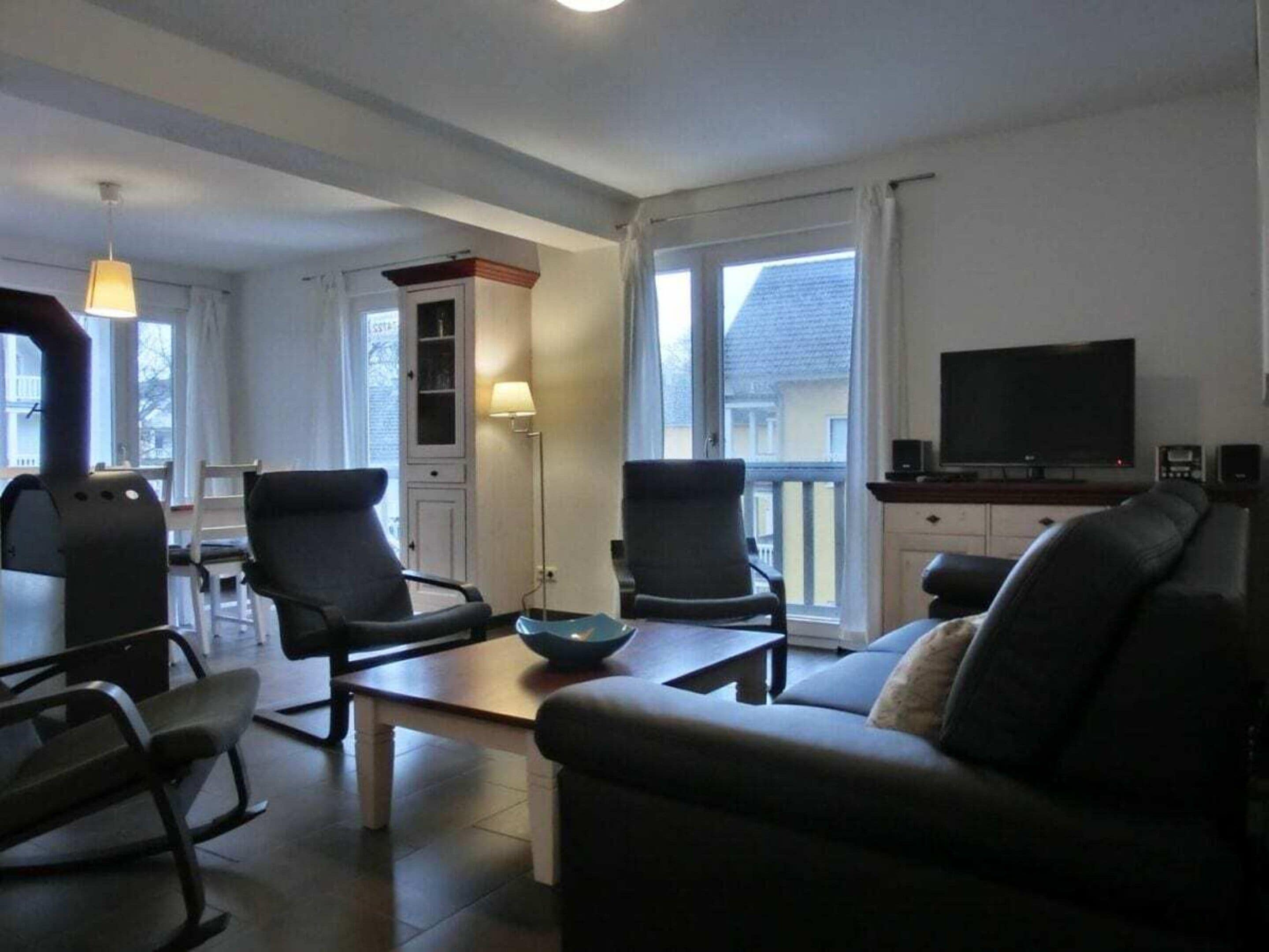 Una sala de estar con un sofá, dos sillones, una mesa de centro, un televisor y una chimenea.