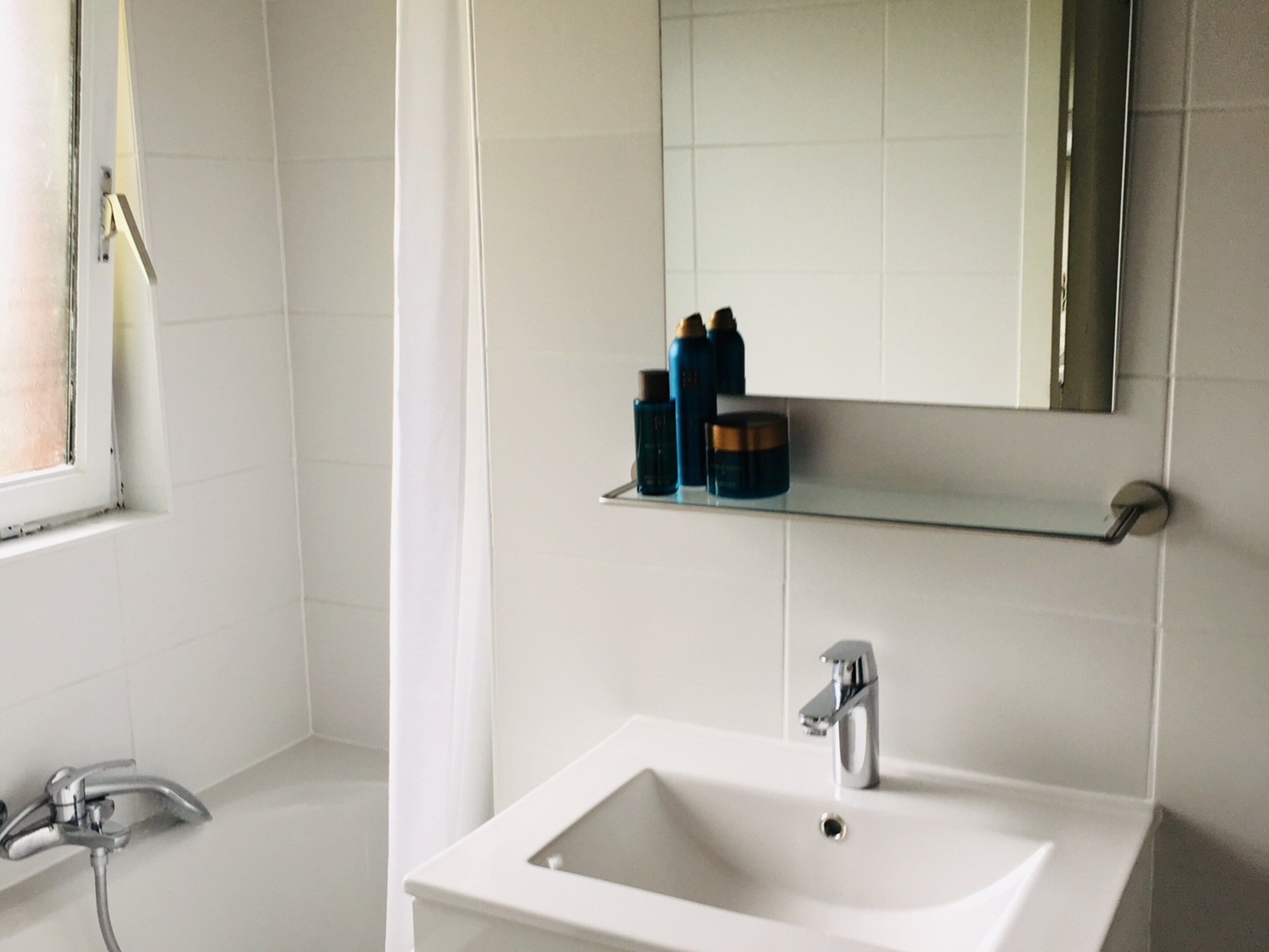 A bathroom with a white sink, a mirror, and a shower.