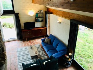 Ein gemütliches Wohnzimmer mit einem blauen Sofa, einem Couchtisch und einem Fernseher.
