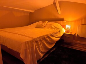 Un dormitorio con cama, mesita de noche y lámpara.