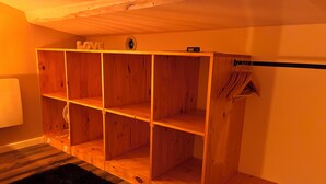 A wooden shelving unit with multiple compartments, a small radio, and a coat rack with hanging items.