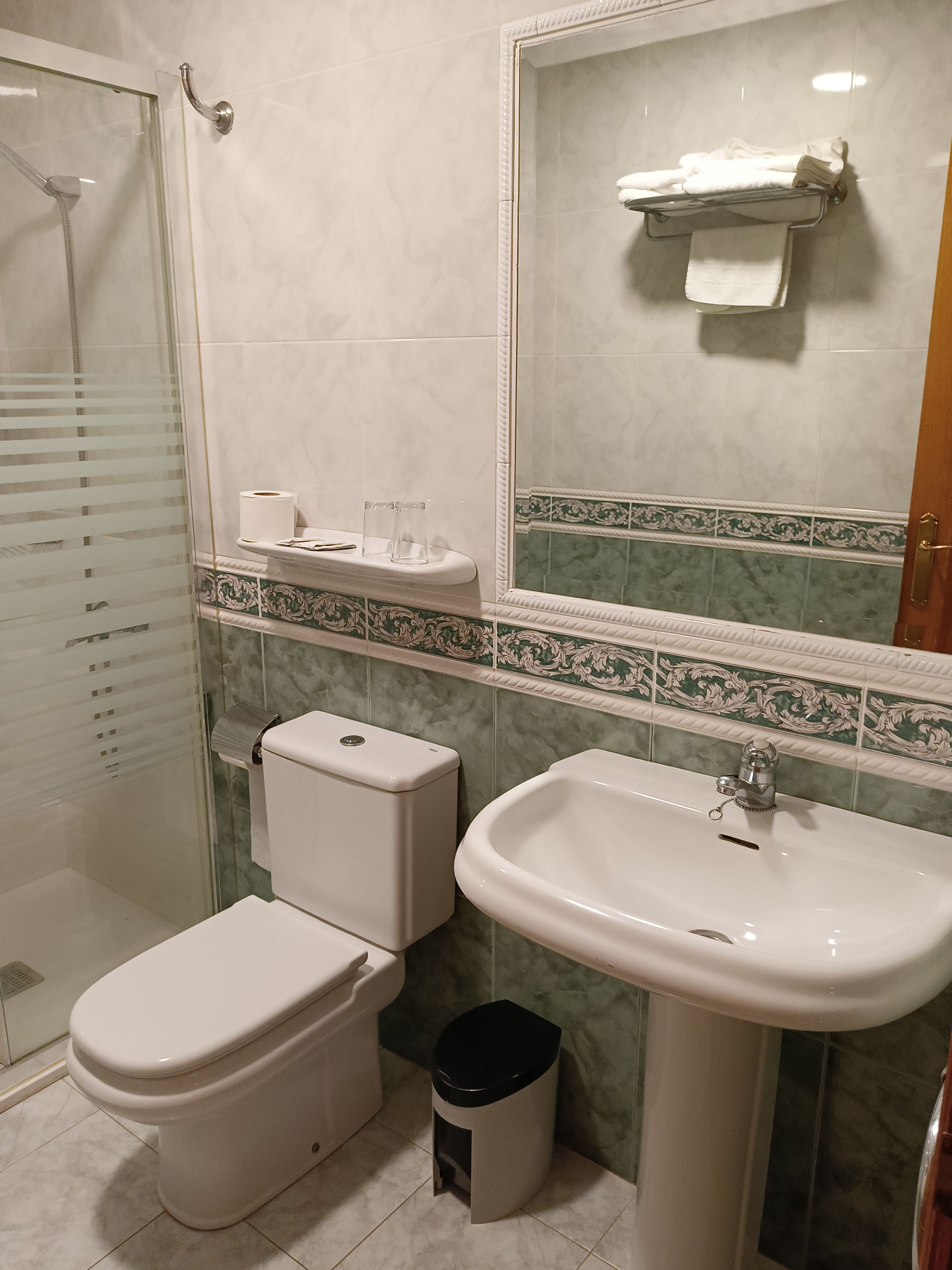 Un baño con inodoro, bidé, lavamanos y cabina de ducha de vidrio.