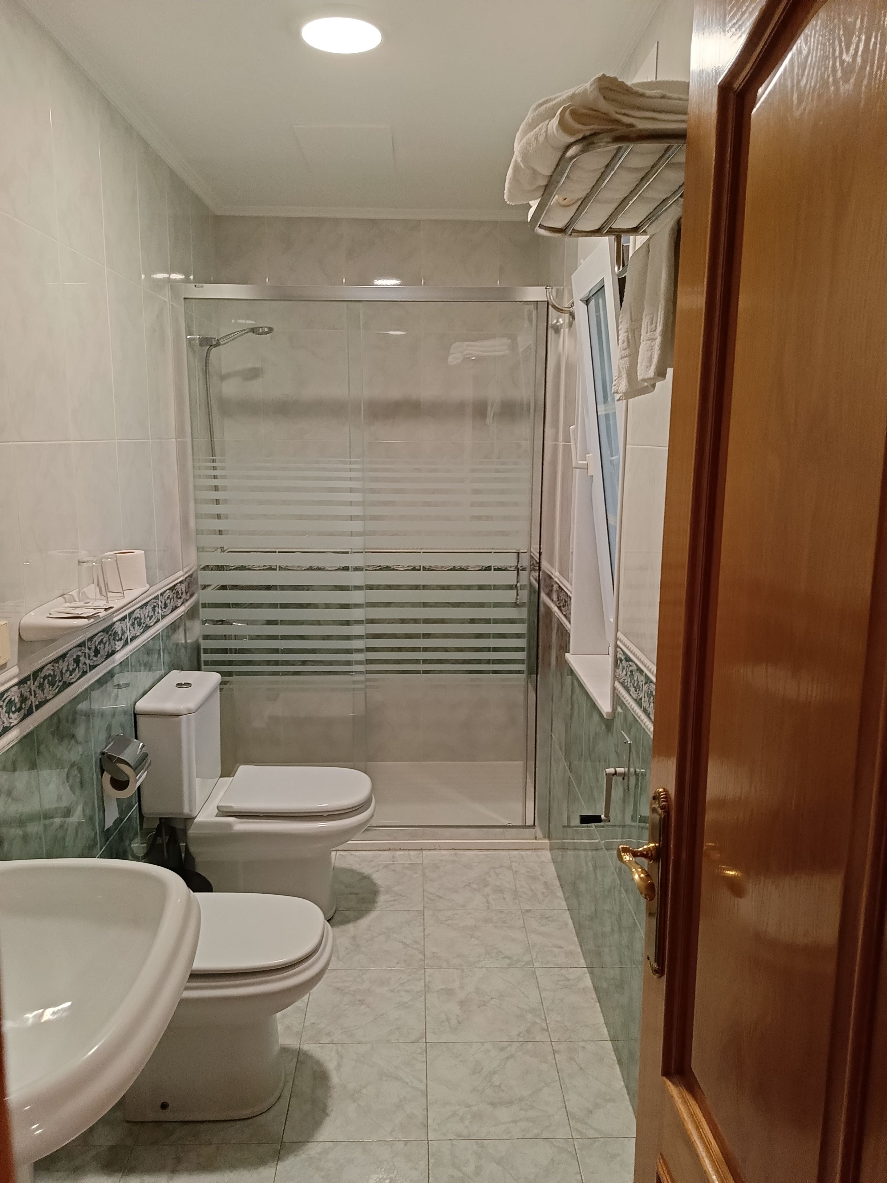 A bathroom with two toilets, a shower enclosure, and a sink.