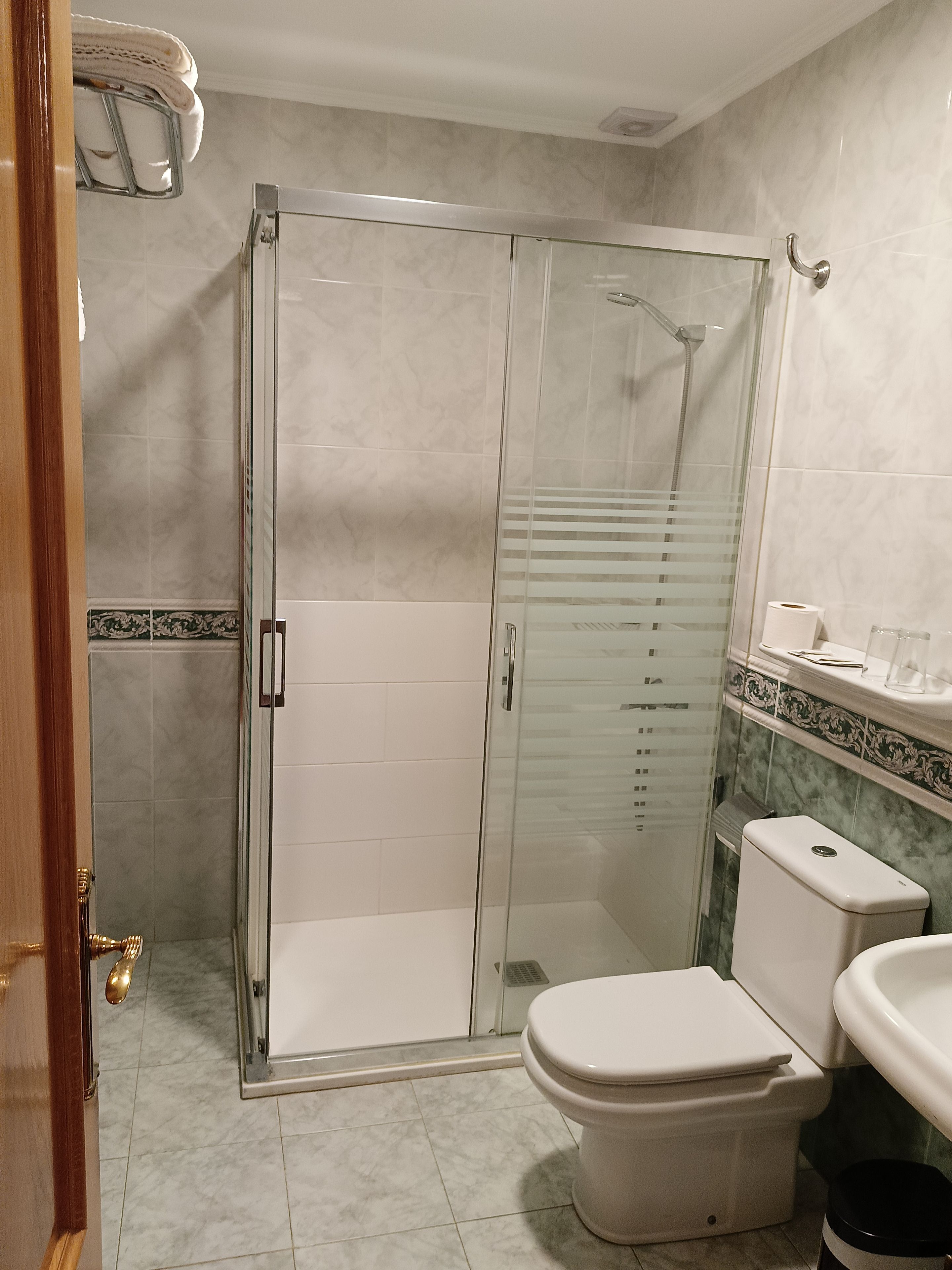 A bathroom with a glass-enclosed shower, a toilet, and a sink.