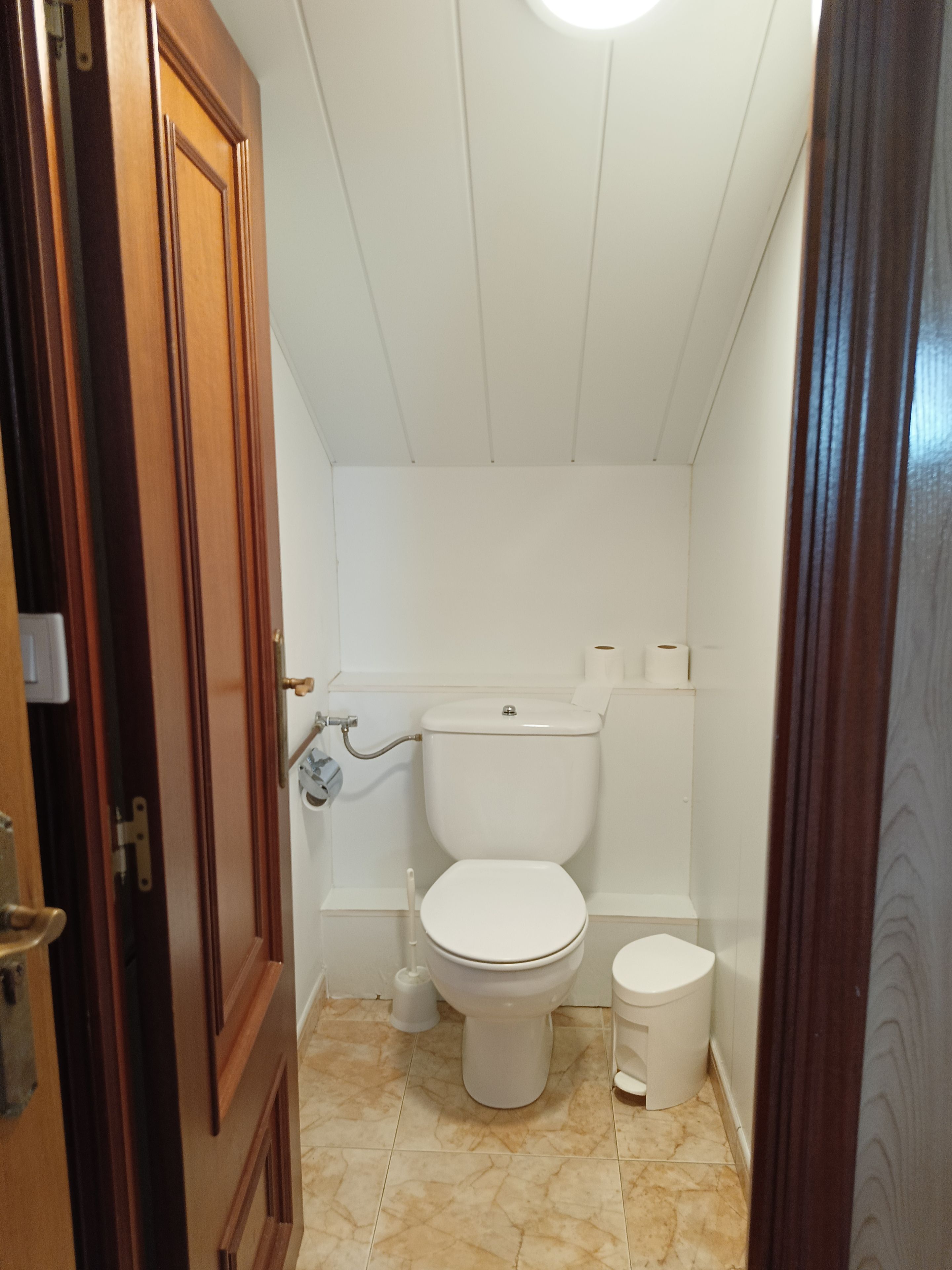 Un baño pequeño y funcional con inodoro blanco, un bidé y un cubo de basura.