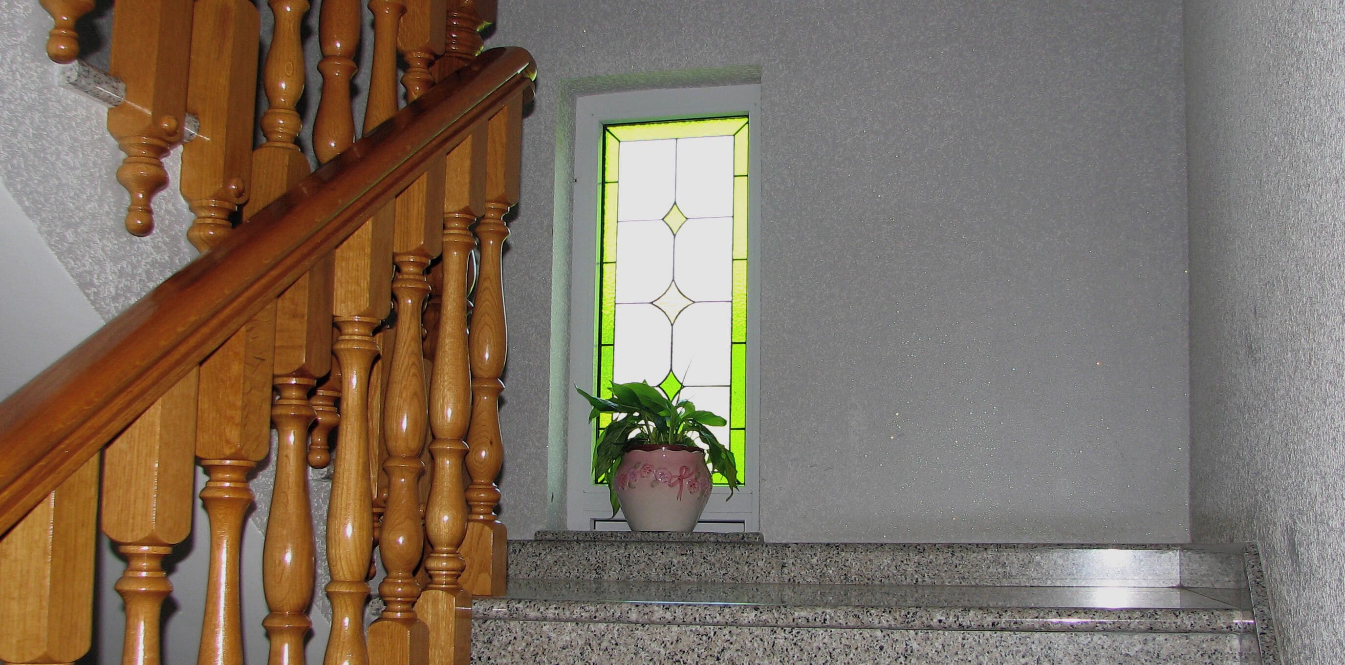 A wooden staircase with a potted plant at the bottom landing.