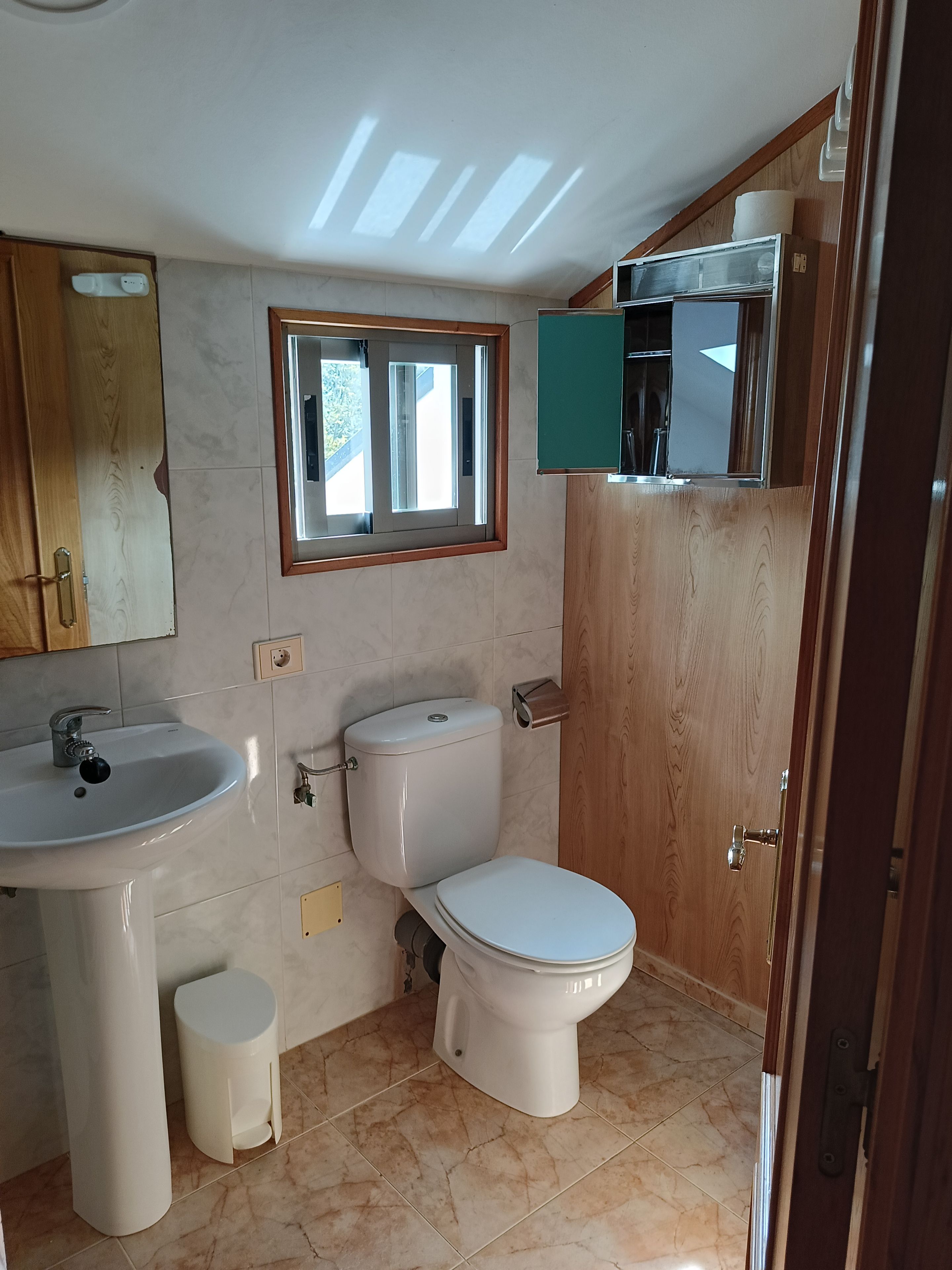 Un baño con inodoro, lavamanos y ventana.