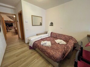 Een slaapkamer met een bed, een spiegel en een houten vloer.