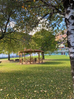 Un parc amb un porxo de fusta, taules de pícnic i bancs.