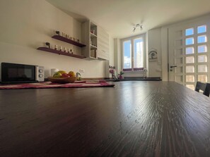 Een keuken met een magnetron, een houten tafel en een schaal met fruit.