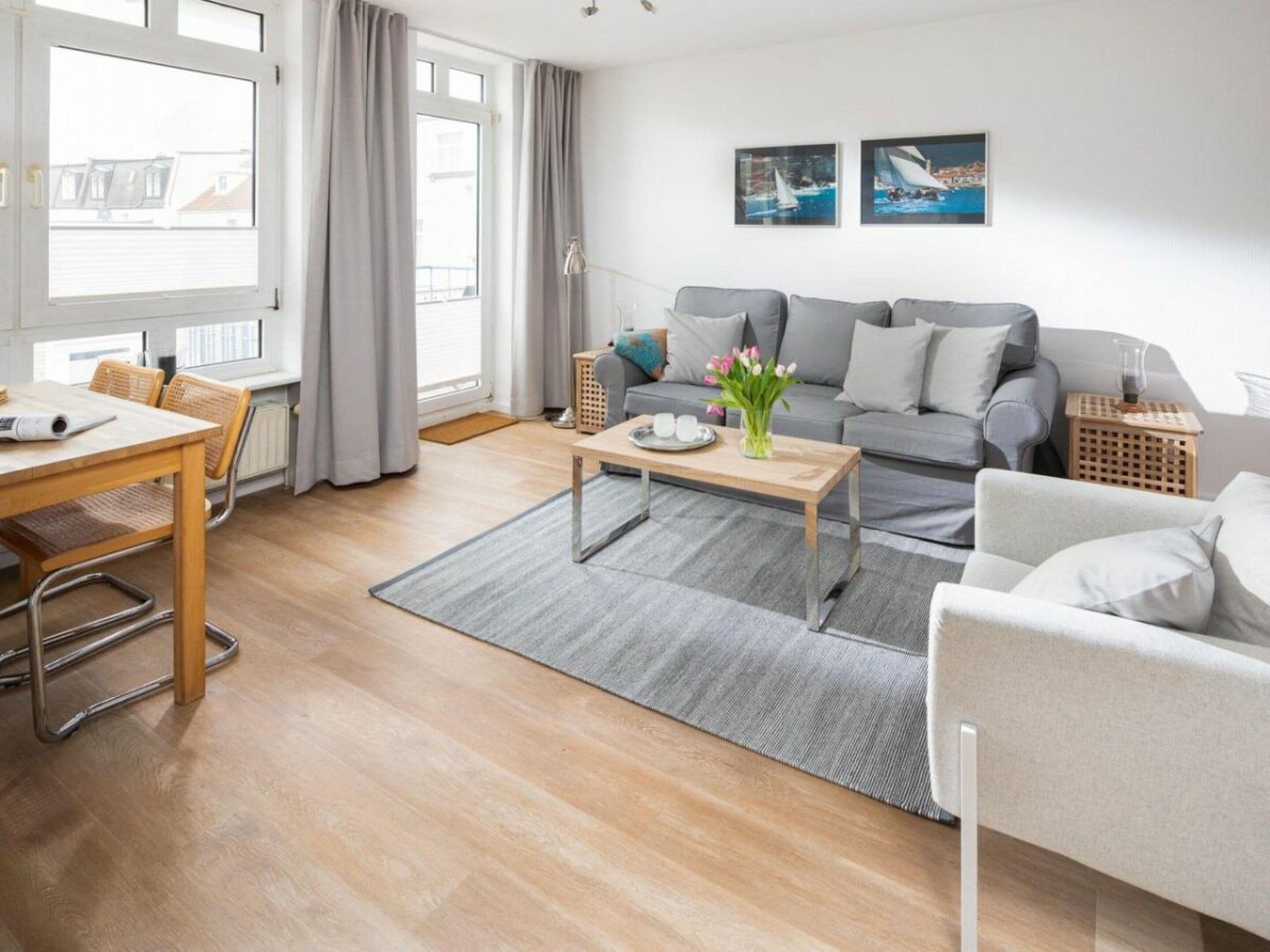 A modern living room with a sofa, coffee table, and a dining area with a table and chairs.
