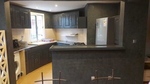 A kitchen with dark cabinets, a refrigerator, a stove, and a sink.