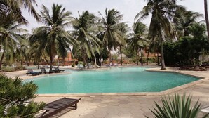 Une piscine entourée de palmiers et de chaises longues.