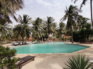 A pool surrounded by palm trees and lounge chairs. - Vrbo Property (Saly)