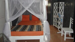 Un lit avec une moustiquaire, un climatiseur, une chaise blanche et une armoire.