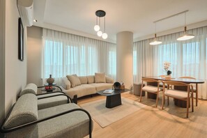 A modern living room with a sofa, coffee table, dining table with chairs, and a large window with curtains. - Polgar, 3br, Welcoming, Charming (Istanbul)