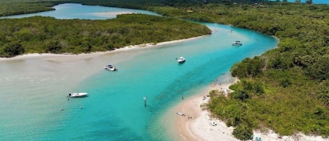 Un paisaje costero con aguas turquesas cristalinas, embarcaciones y una playa arenosa.